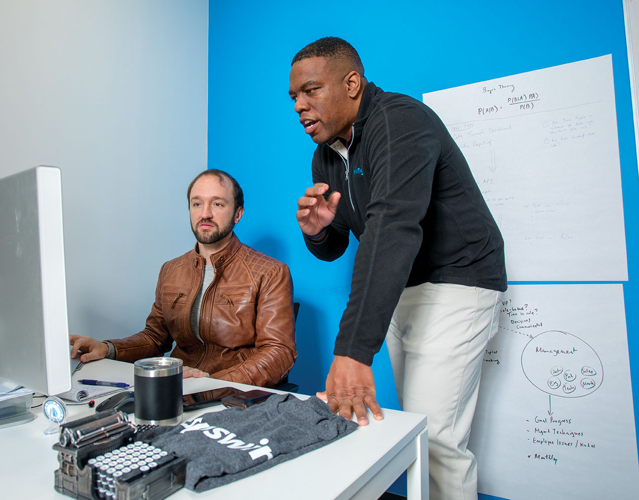 Melvin Hines standing beside a seated Alex Pritchett during a conversation at Upswing