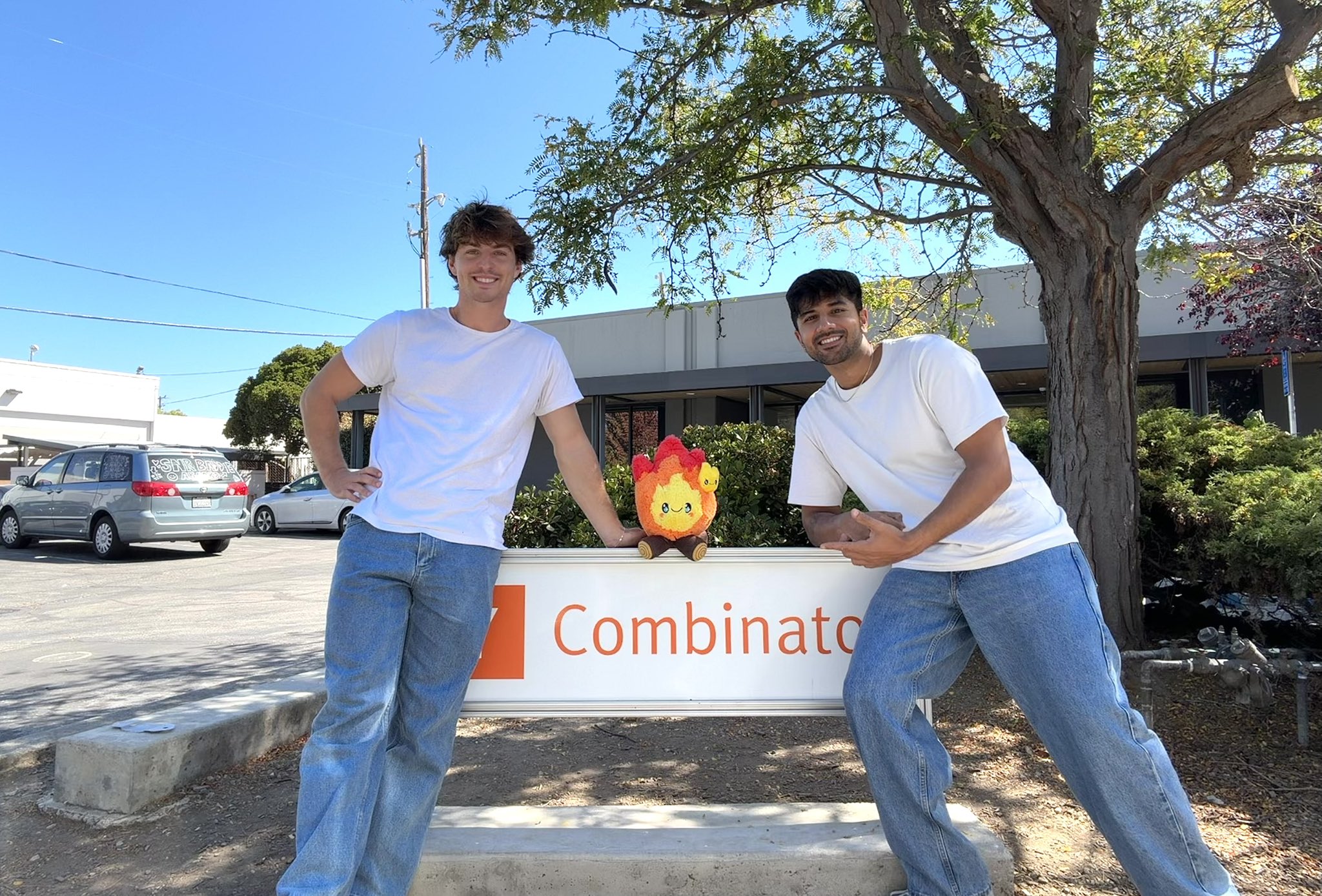 Alex Ruber and Parth Chopra standing beside the Y Combinator sign with Candle's flame mascot