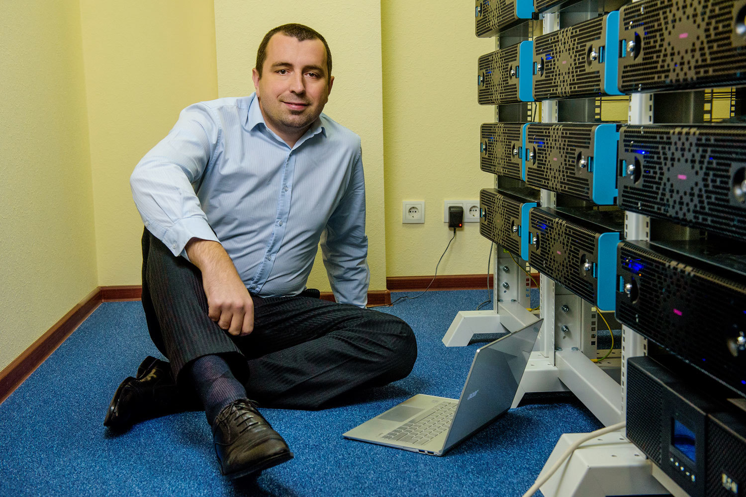 Alexander Katashov sitting beside data-storage equipment with an open laptop