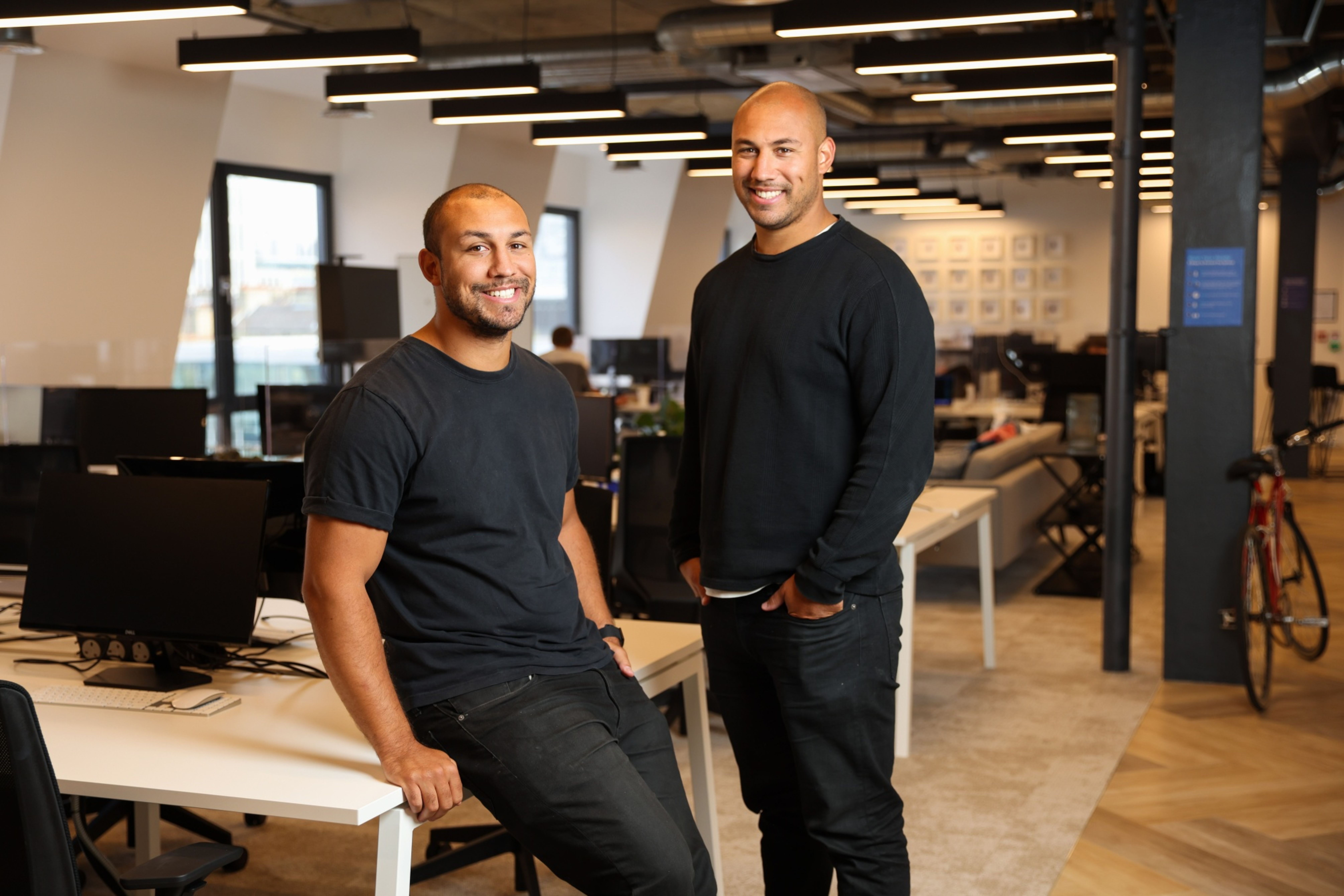 Alexander Kent-Braham seated on a desk at left, with twin Oliver standing beside him in the Marshmallow office