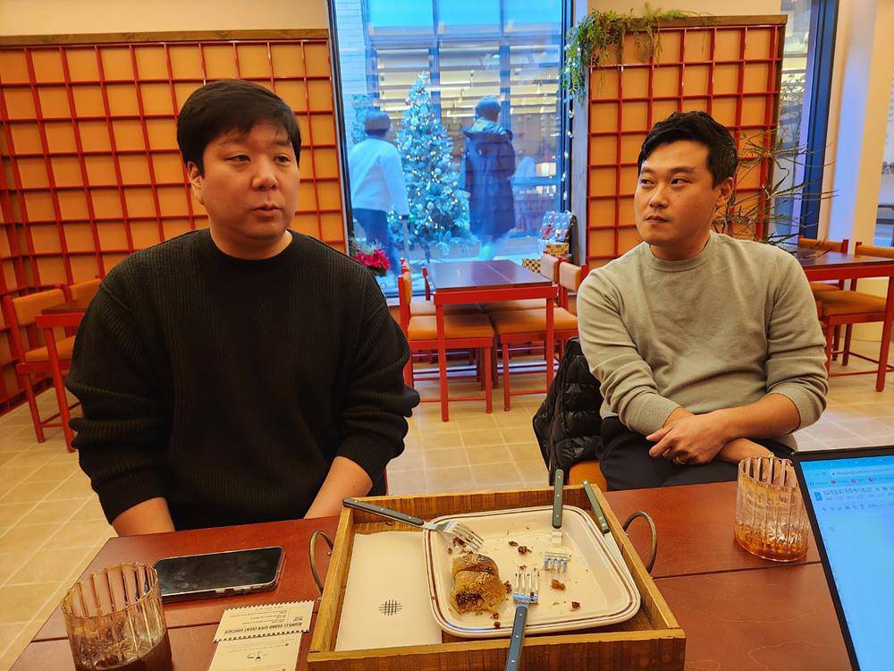 Alexander Min, left, and The Bread Blue founder Moon Dong-jin sitting at a bakery table
