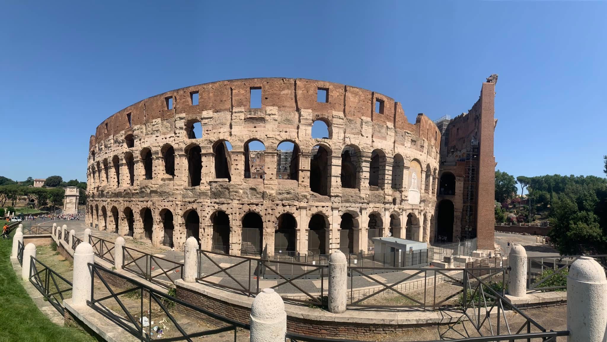 Wide view of the Colosseum in Rome under a clear blue sky