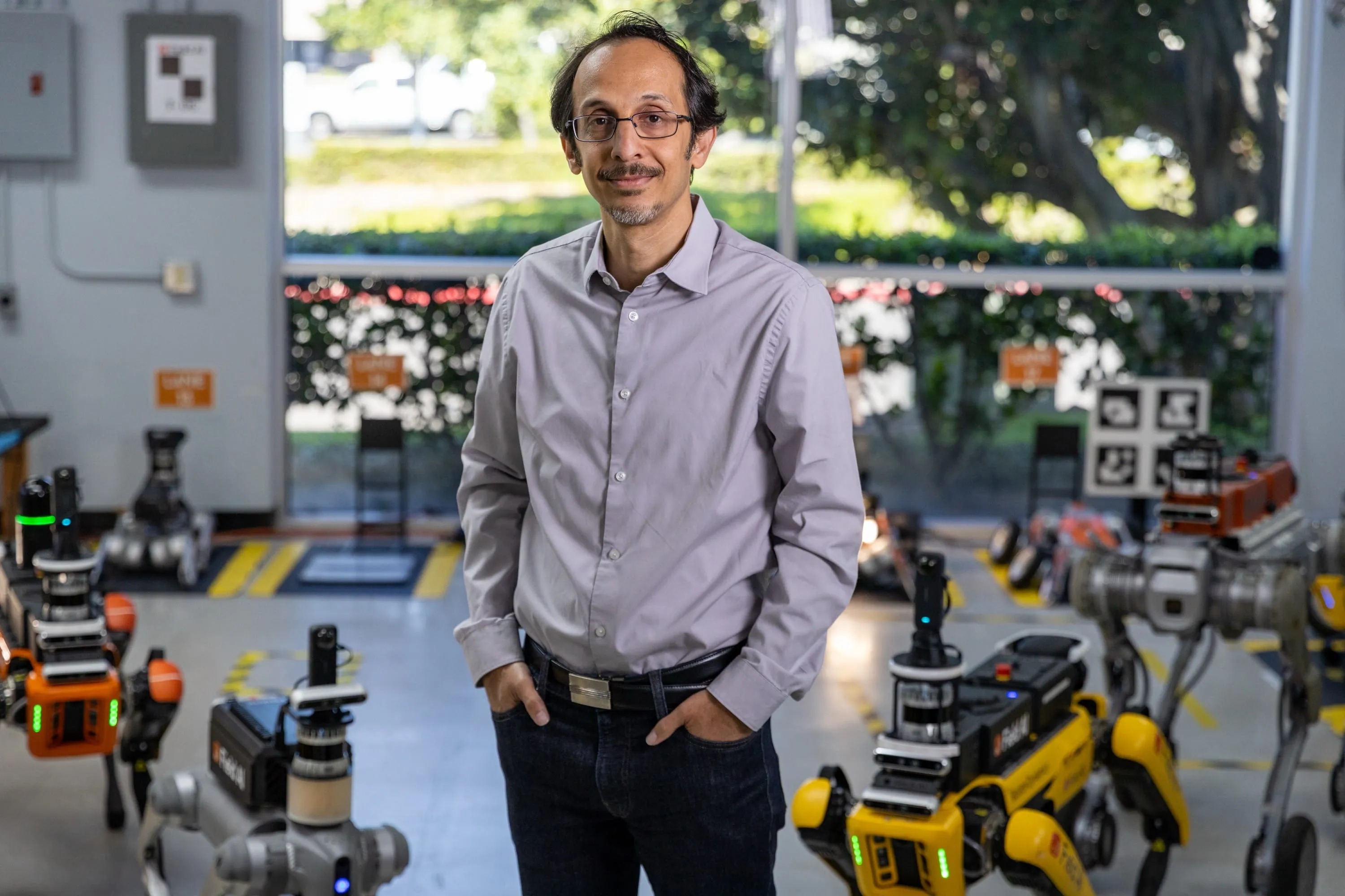 Ali Agha standing among FieldAI robots in the company's lab