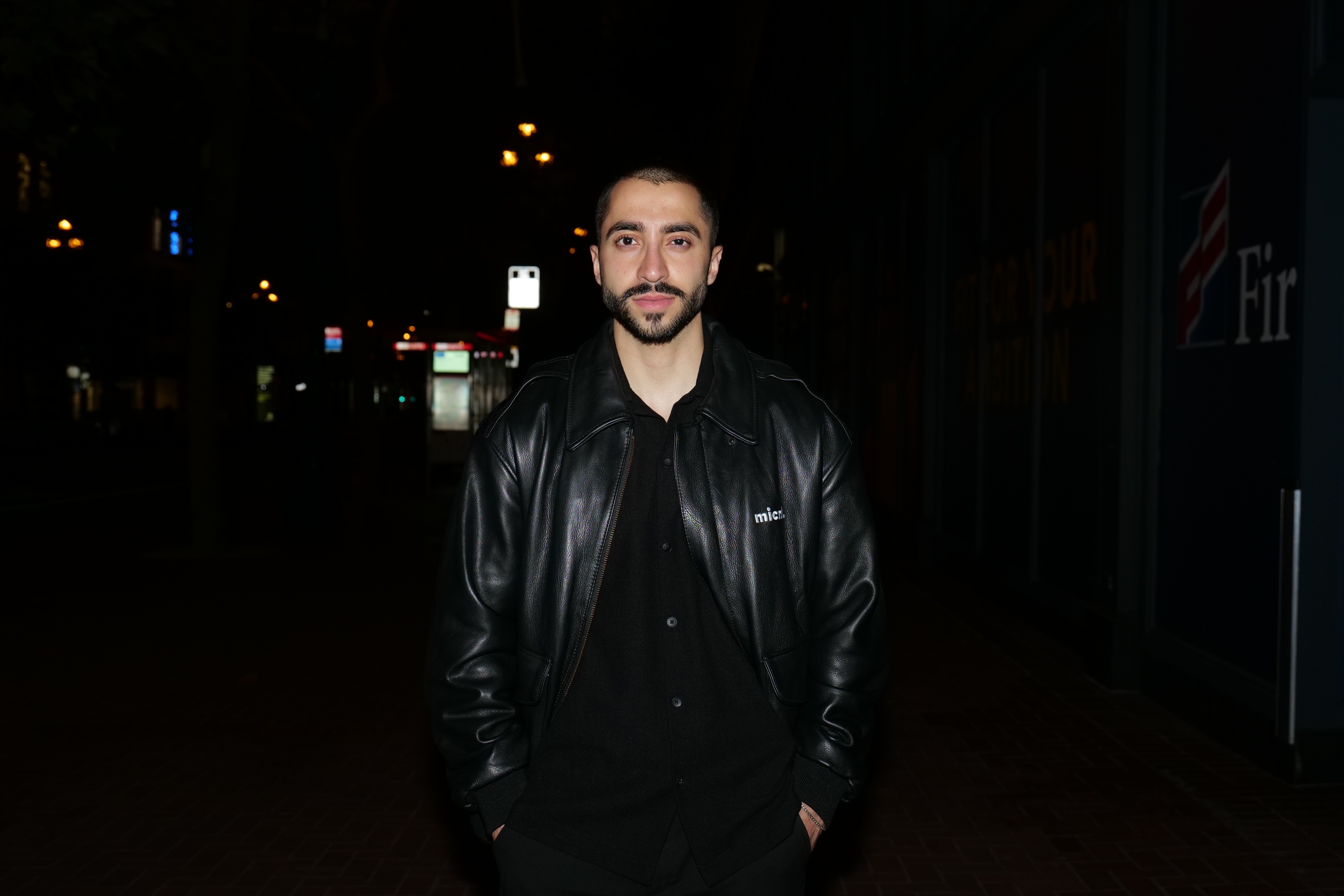Ali Ansari wearing a black micro1 jacket on a city street at night