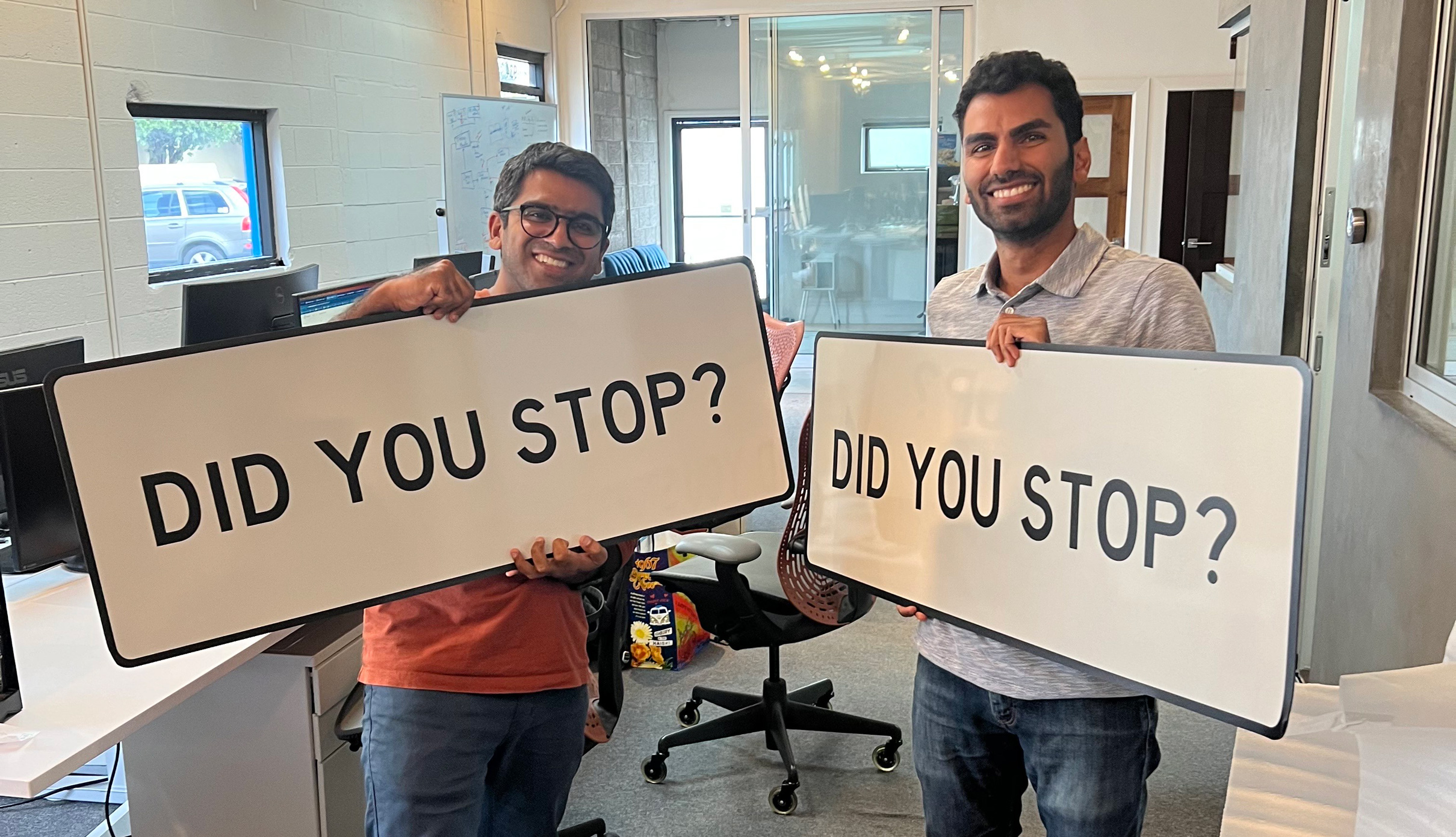 Ali Rehan on the left and Dhruv Maheshwari holding DID YOU STOP? signs in an office