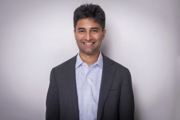 Ali Shaikh standing in a dark jacket and light checked shirt