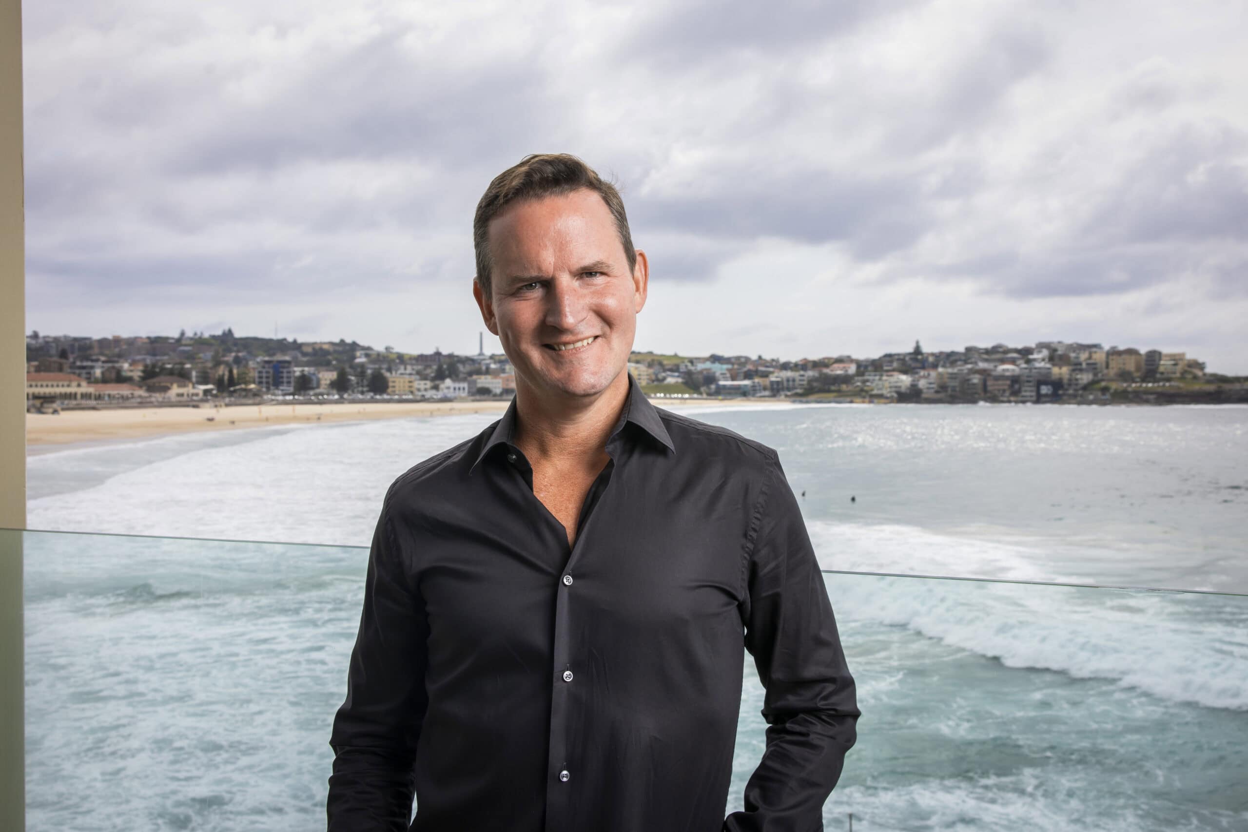 Alisdair Faulkner standing in front of a beach and ocean