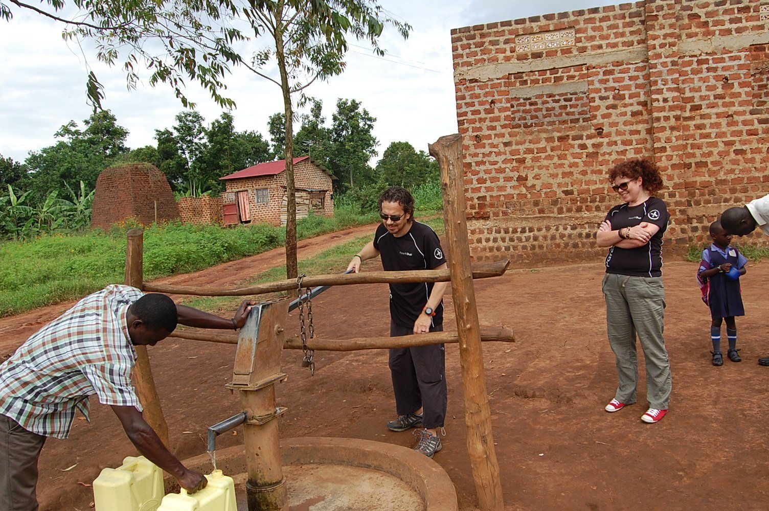 People working beside a brick school building in a Parenta Trust gallery photograph