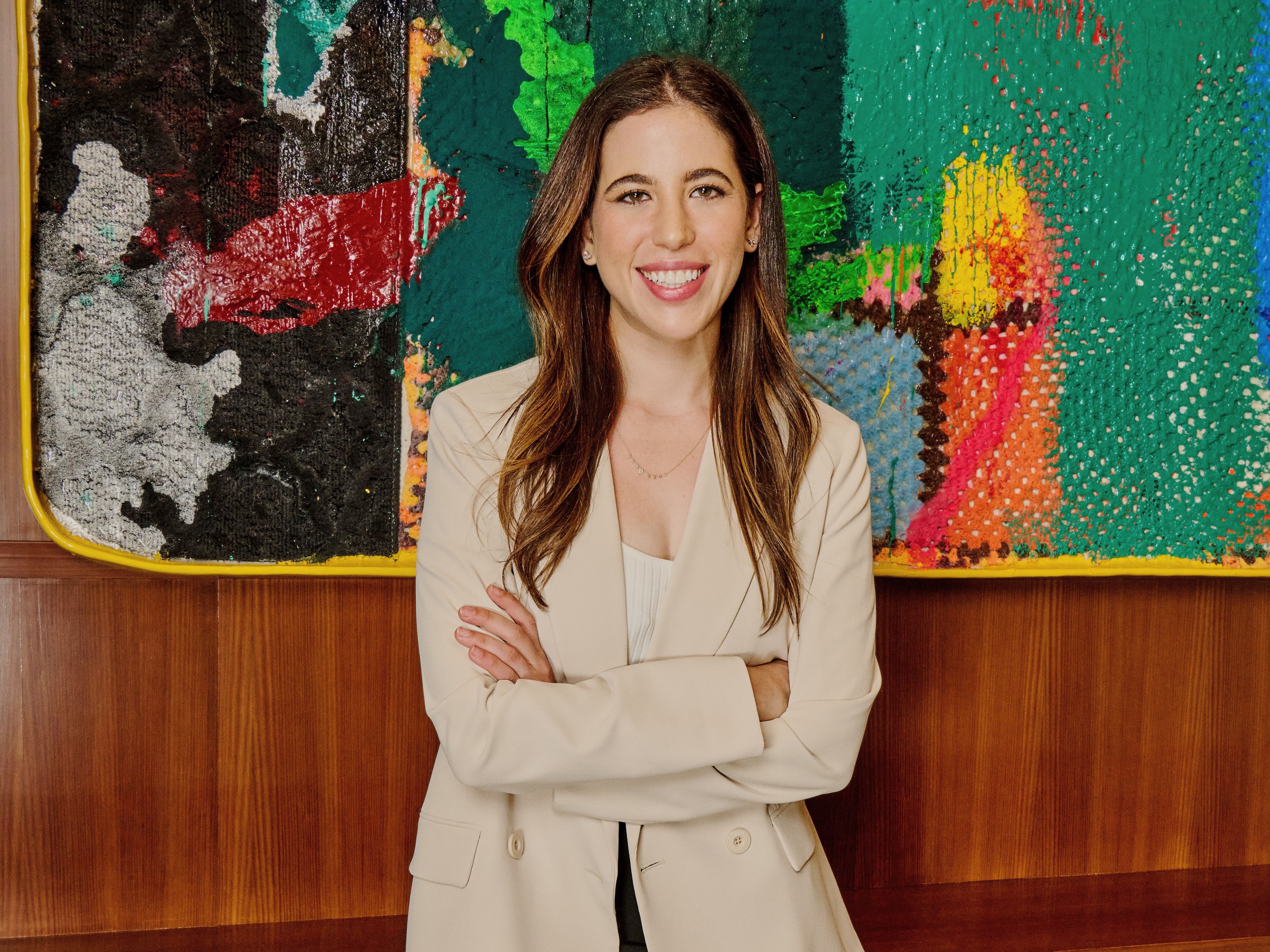 Allara founder Rachel Blank standing in front of a colorful abstract painting