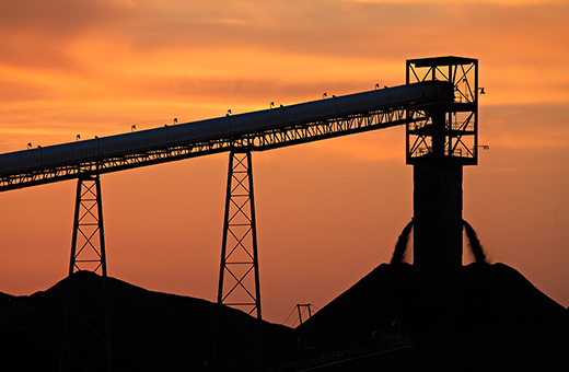 River View coal conveyor and stockpiles silhouetted against an orange sky