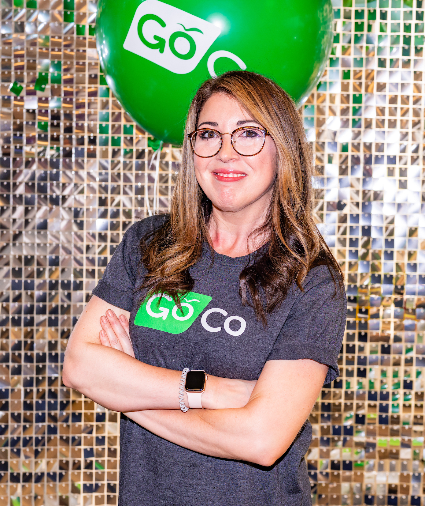 Allie Collins at a GoCo event, standing before a green balloon and mirrored backdrop