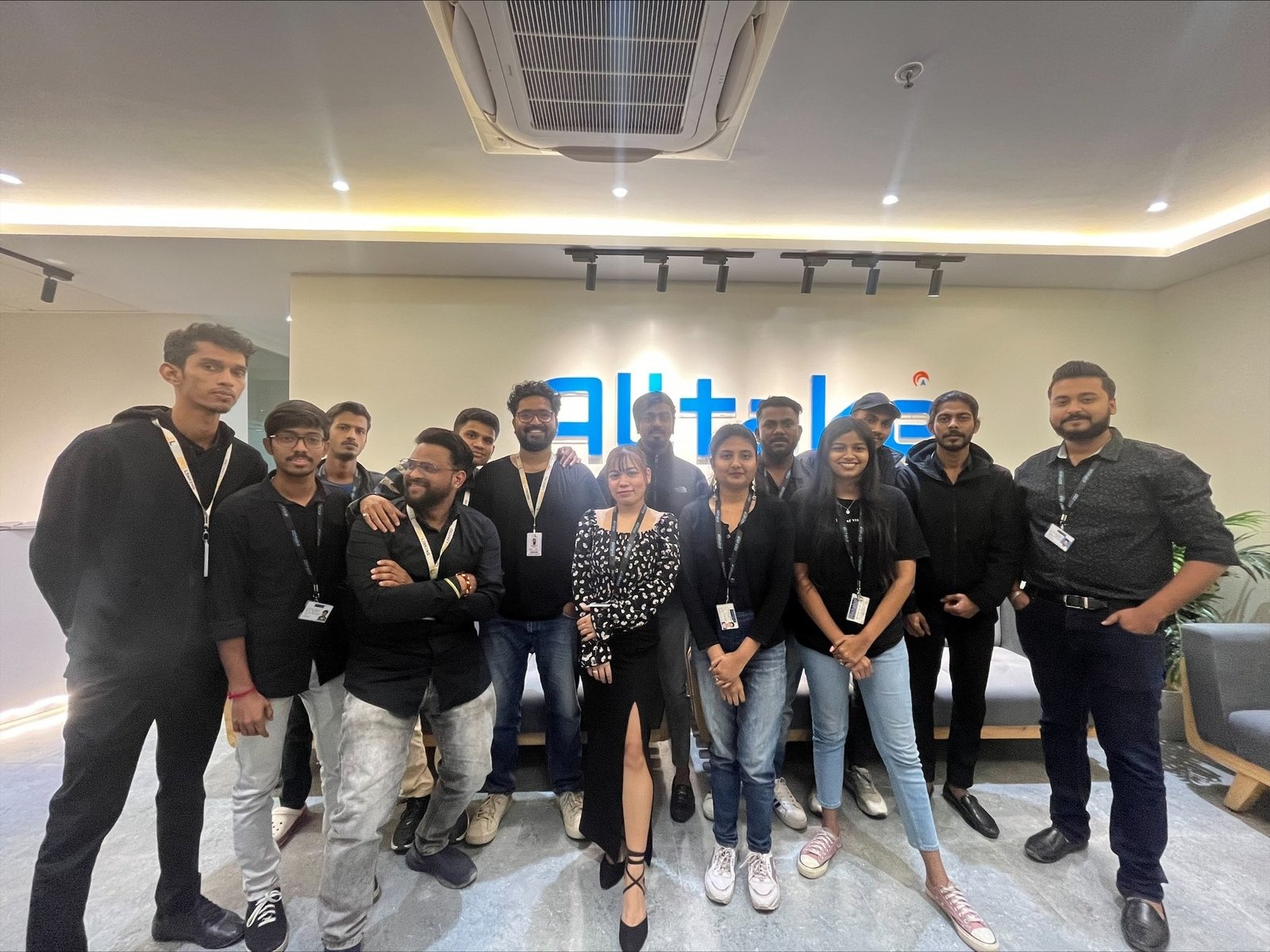 Alltake employees gathered in an office in front of the company name