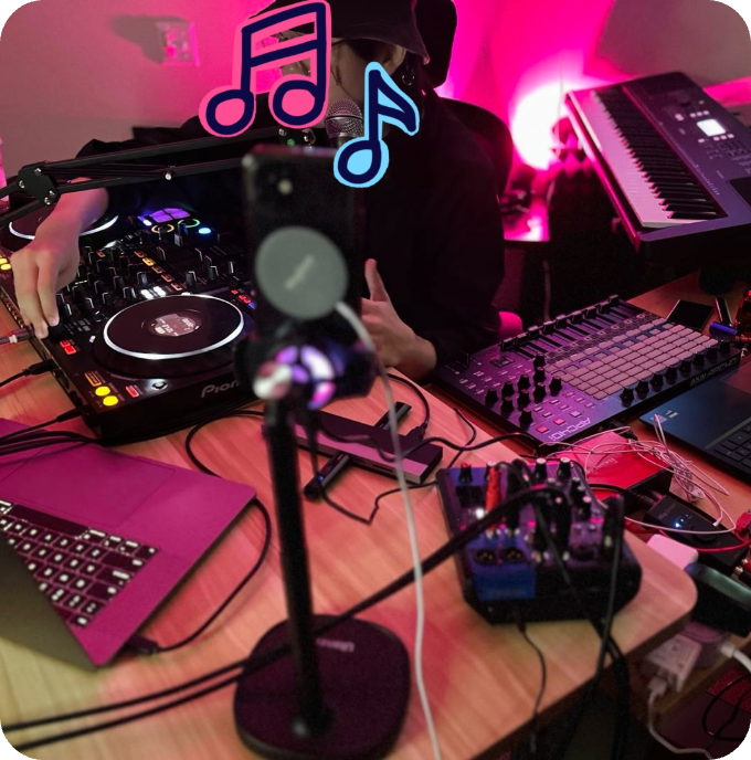 Alta promotional image of a musician surrounded by a microphone, keyboards, mixing equipment and a phone