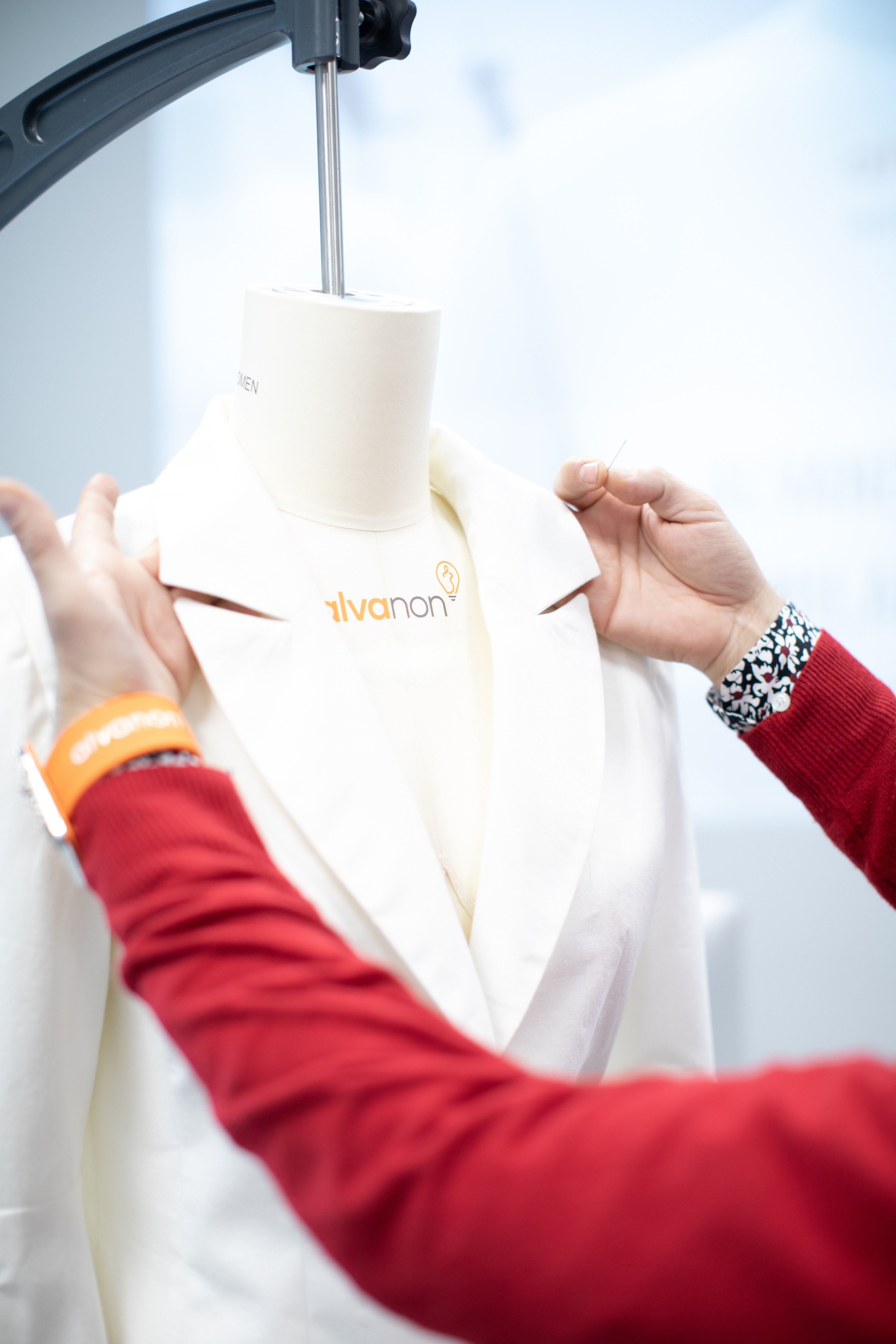 Hands adjusting a white garment on an Alvanon physical fit form