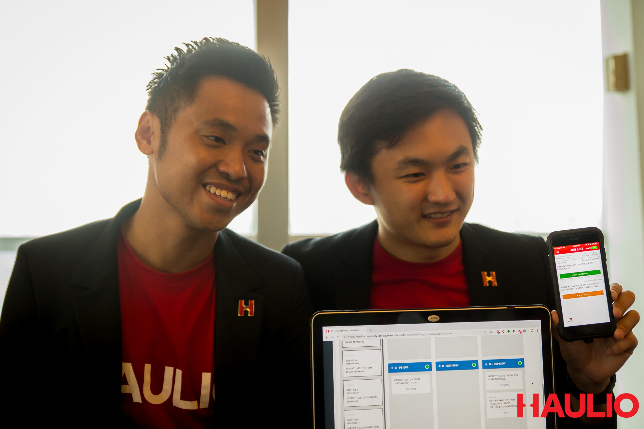 Alvin Ea, left, and Sebastian Shen showing a laptop and smartphone running Haulio software