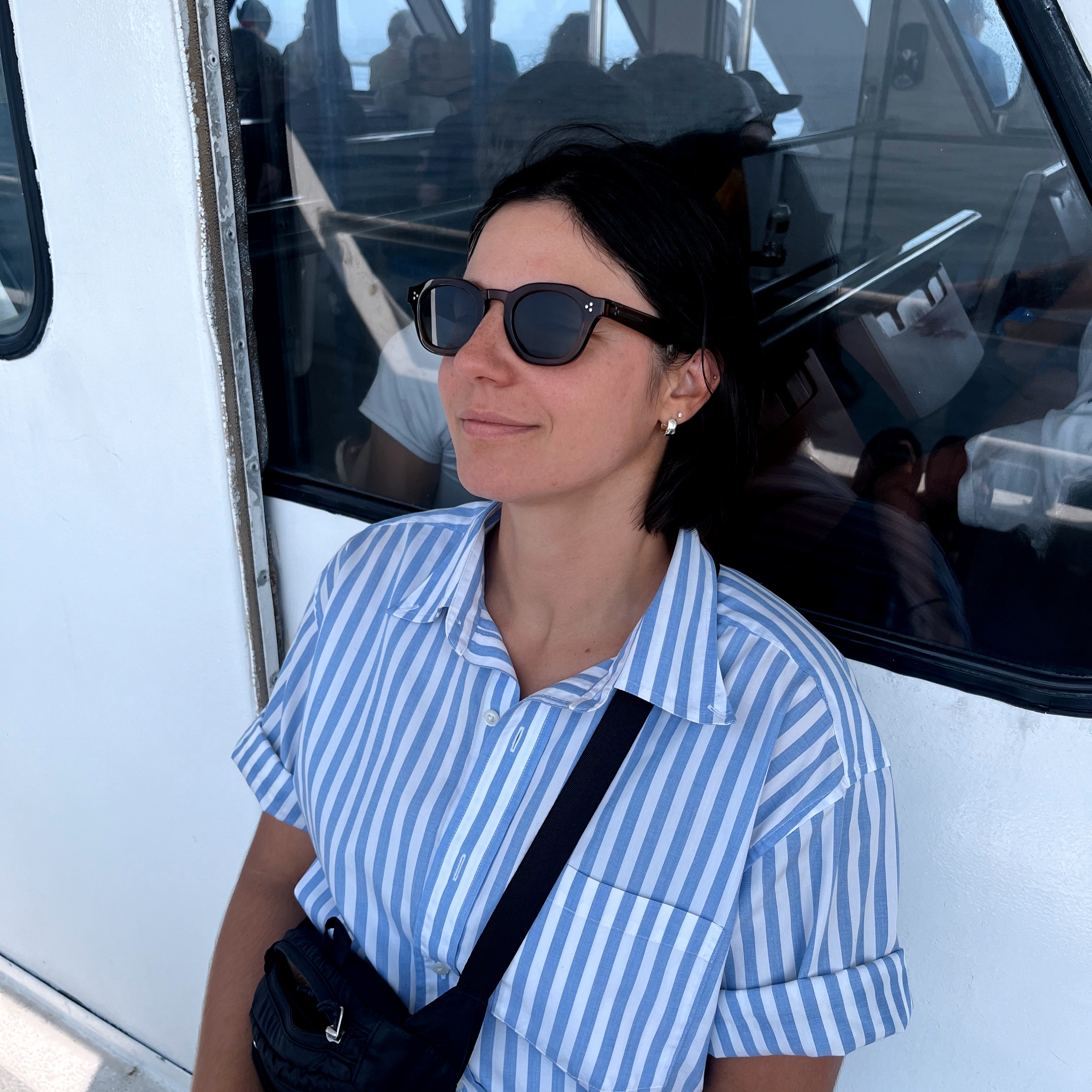 Alysha Daytner in sunglasses and a blue striped shirt aboard a boat