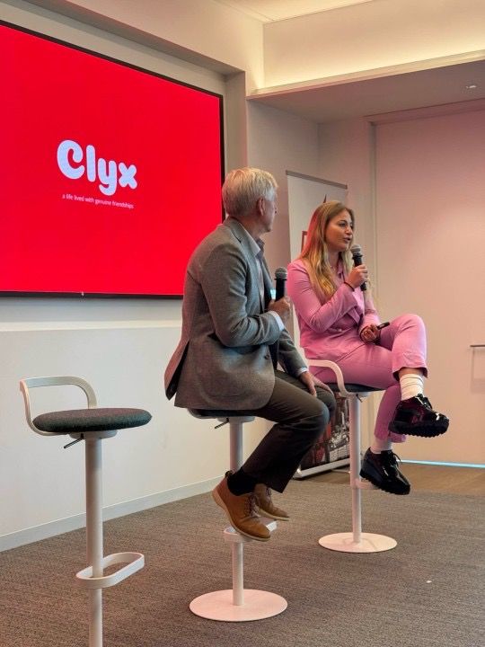 Alyx van der Vorm, wearing pink and holding a microphone, speaks beside another participant at the Blitzscaling Ventures AGM.