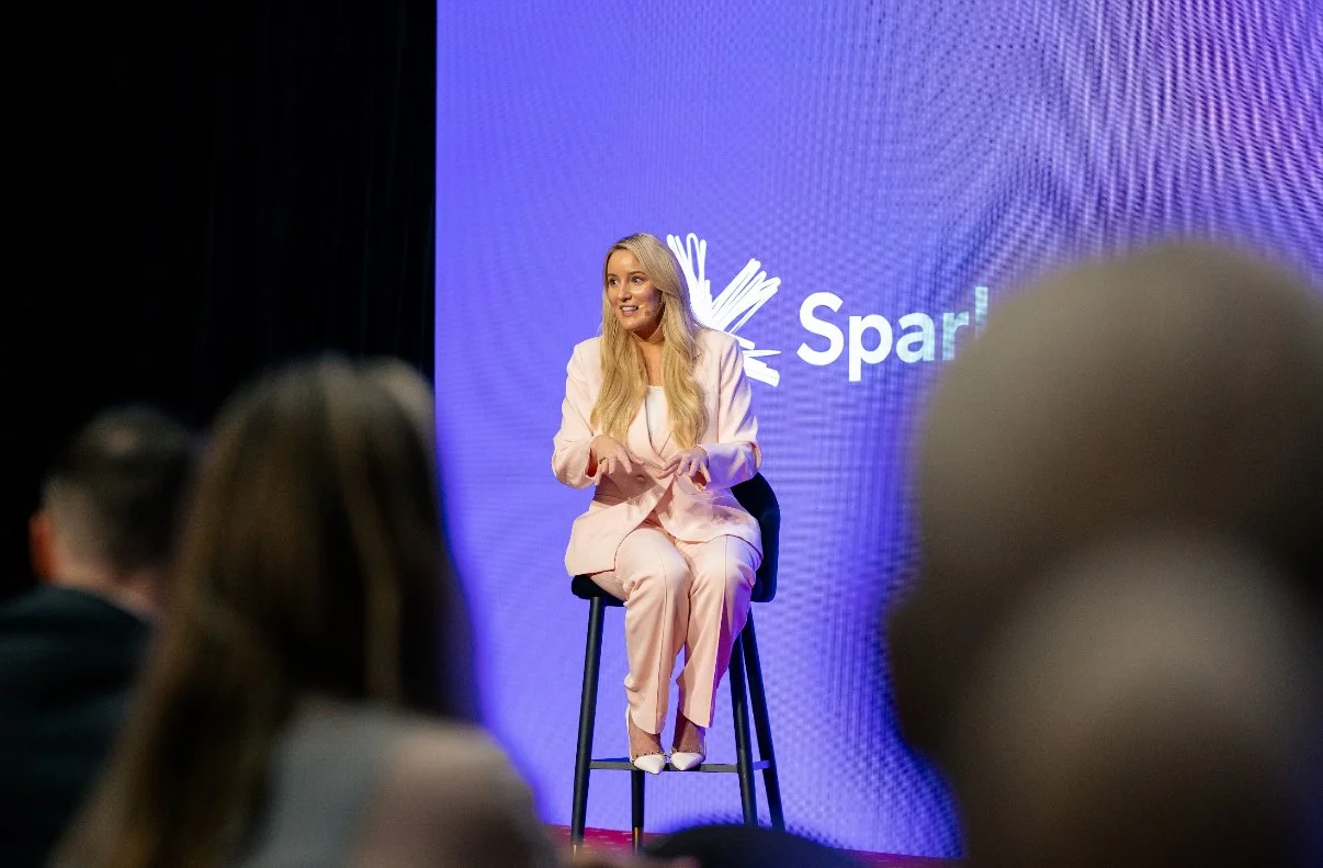 Amanda Johnstone speaking while seated on a stool at a Spark event