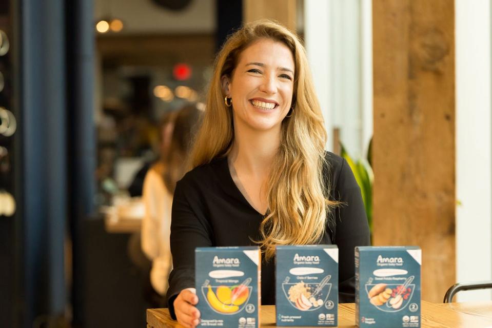 Amara founder Jessica Sturzenegger seated behind three boxes of baby food