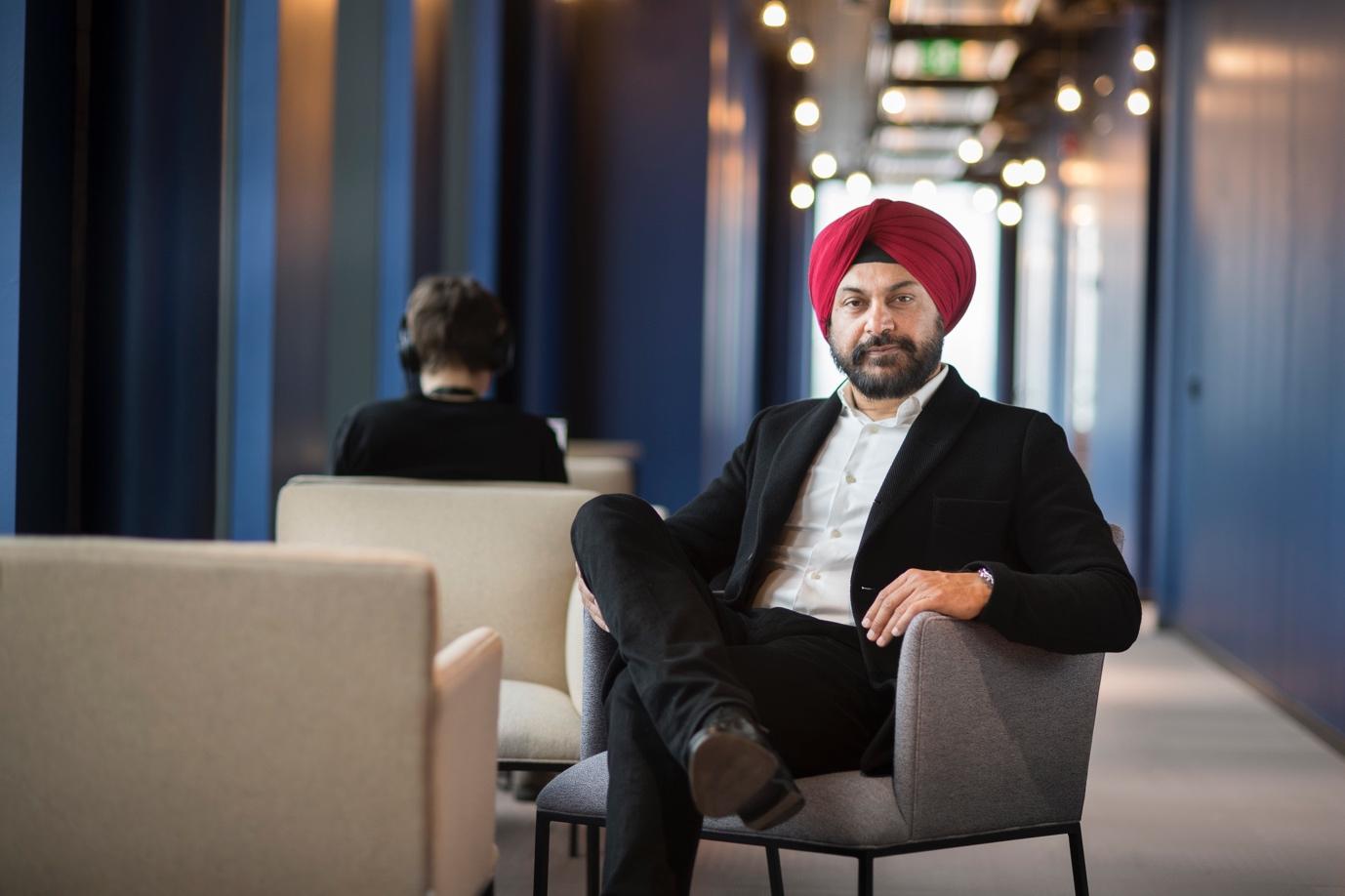 Amarjit Singh Batra seated in an armchair in a blue-walled office corridor, in Spotify’s 2019 press photograph.