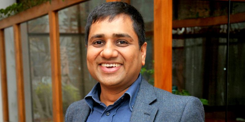 Ambarish Gupta smiling in a blue jacket in a press photograph