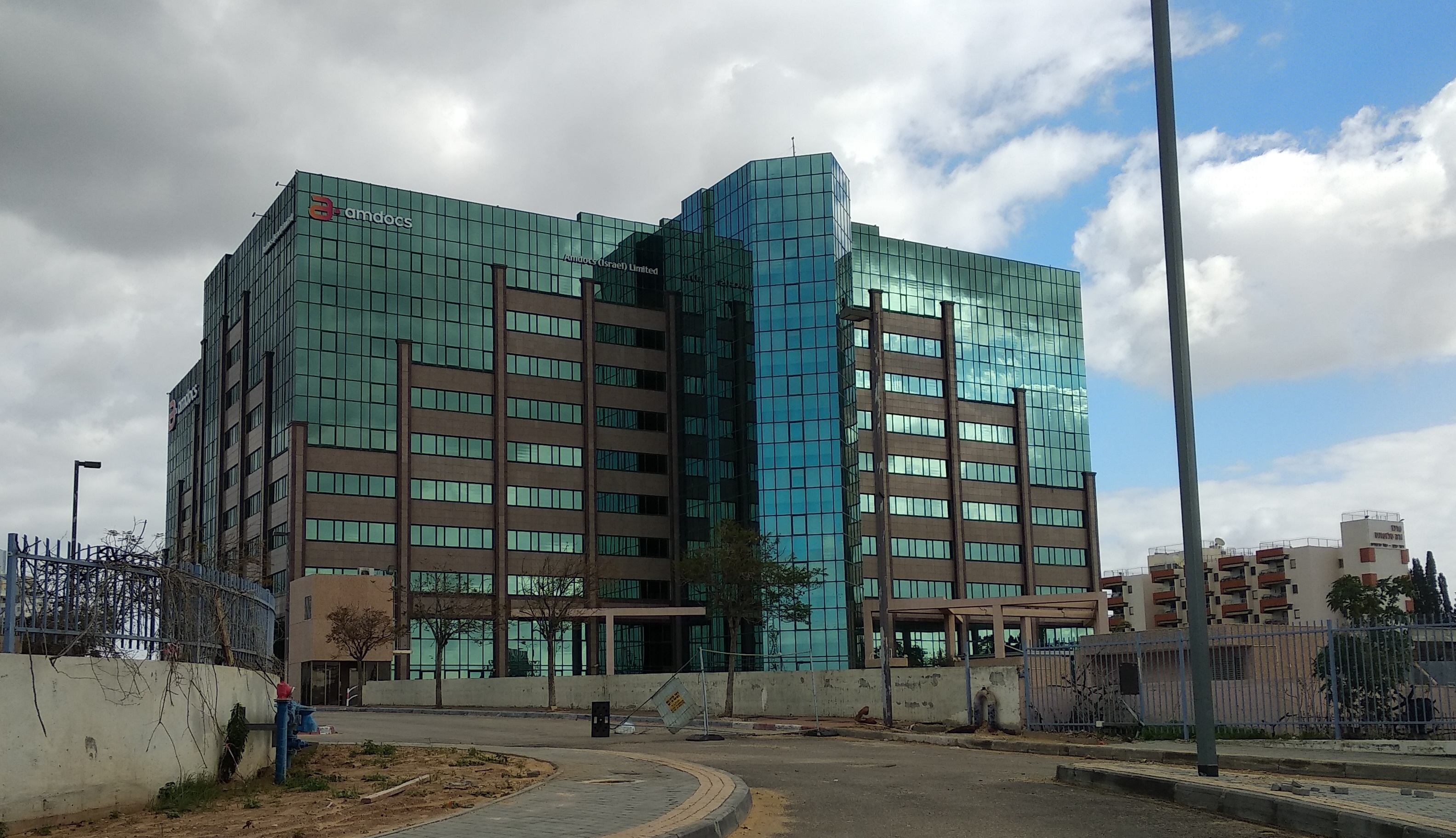 Amdocs office building in Ra'anana, Israel beneath a partly cloudy sky