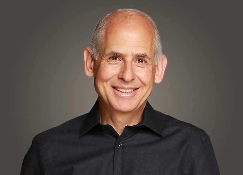 Daniel Amen smiling in a black shirt against a gray background