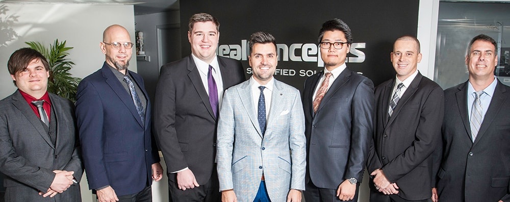 Seven members of the technology team pictured in front of Ideal Concepts signage