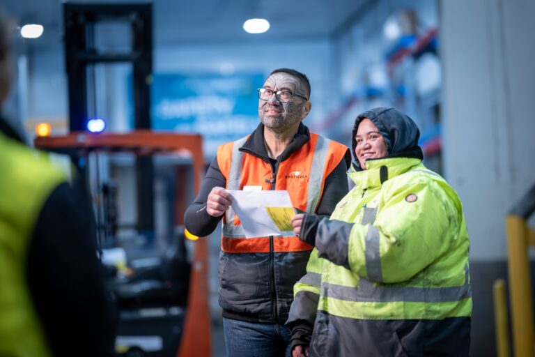 Americold warehouse associates reviewing a document in safety clothing