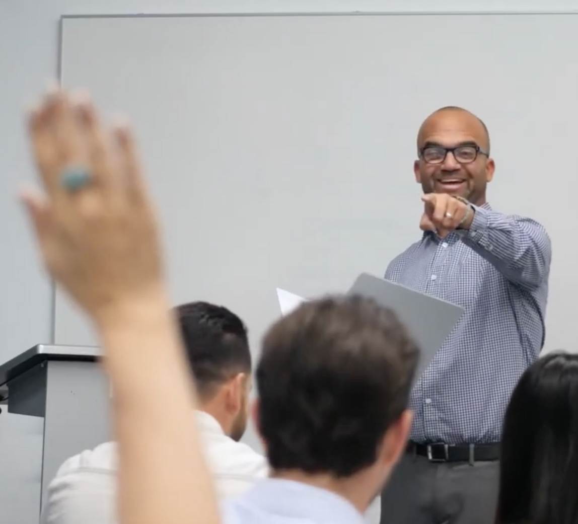 A trainer points toward employees during a company training session