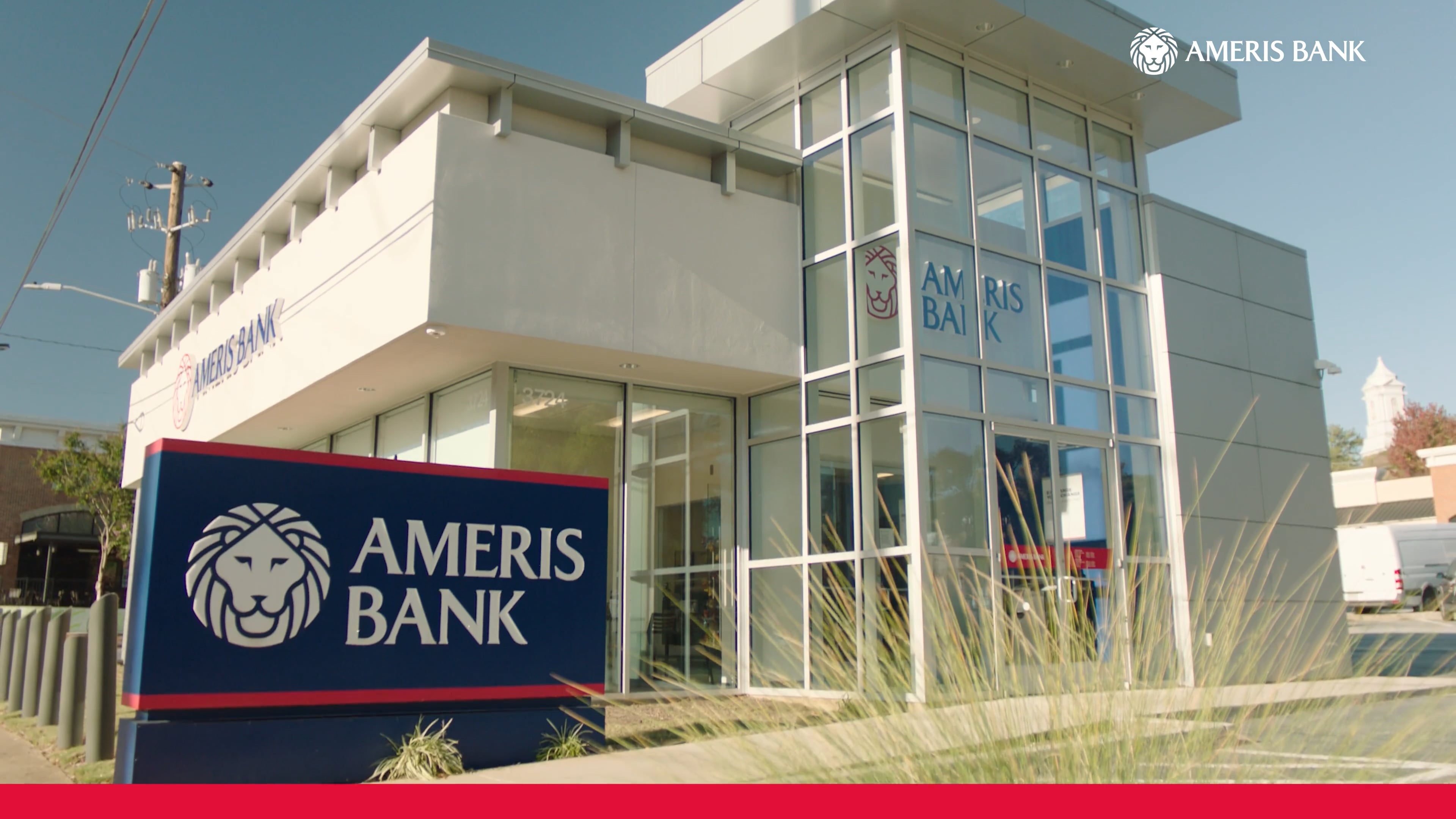 Ameris Bank branch exterior with a glass entrance, ornamental grasses and lion signage