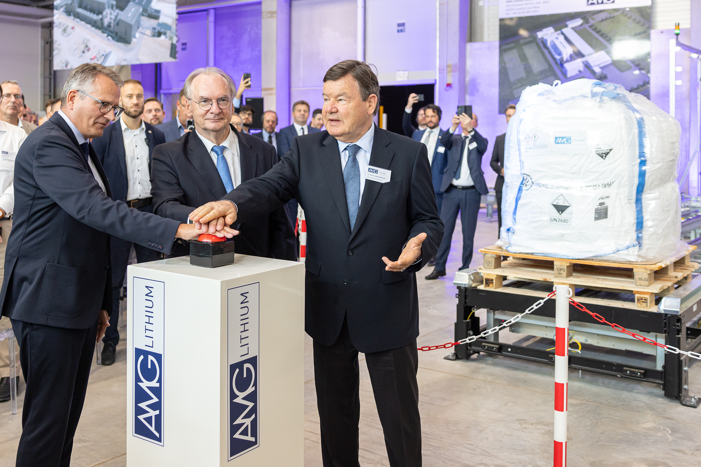 Three executives and officials press the ceremonial start button beside a bag of lithium product at Bitterfeld