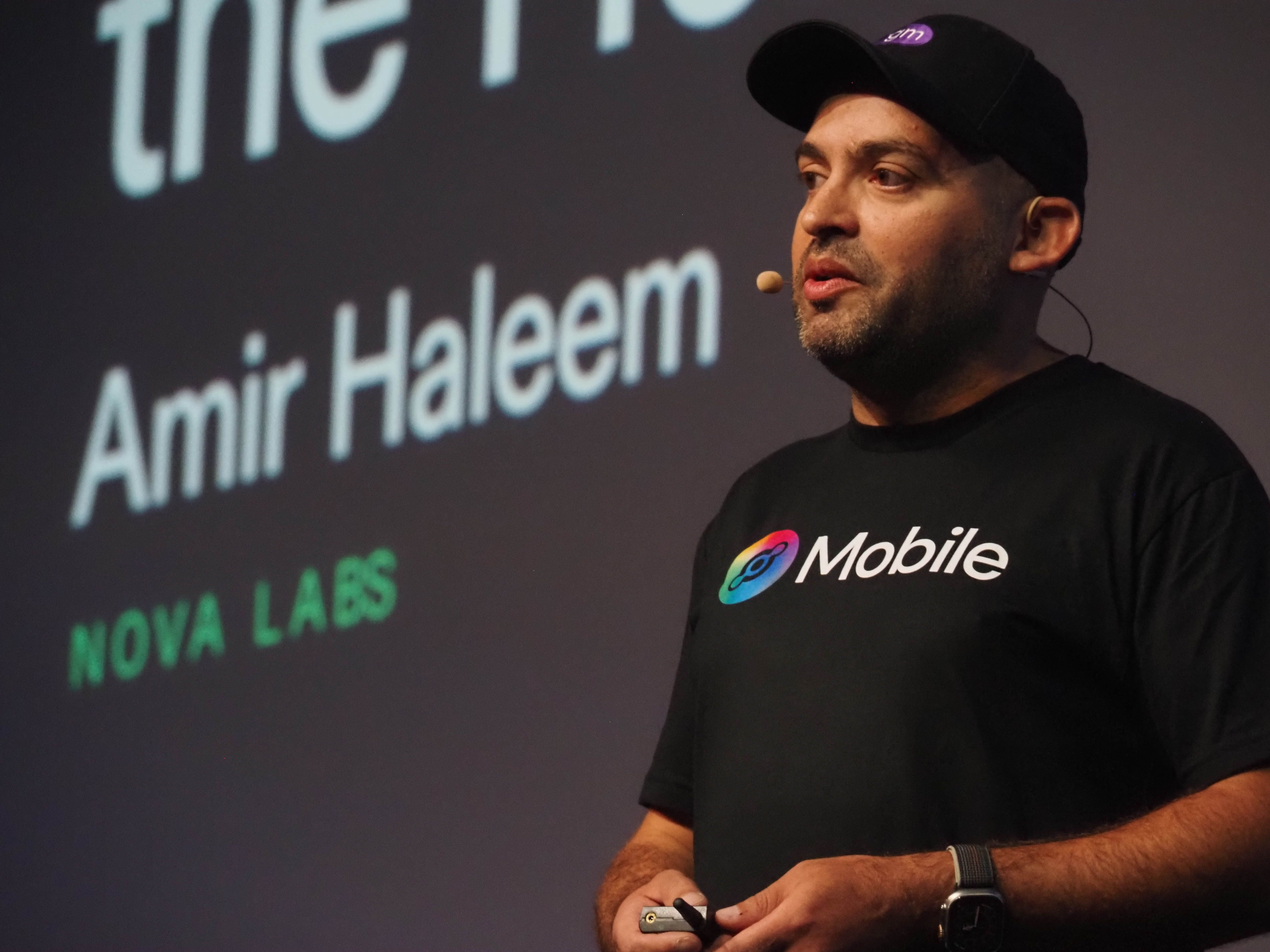 Amir Haleem speaking on stage at Solana Breakpoint in a Helium Mobile T-shirt