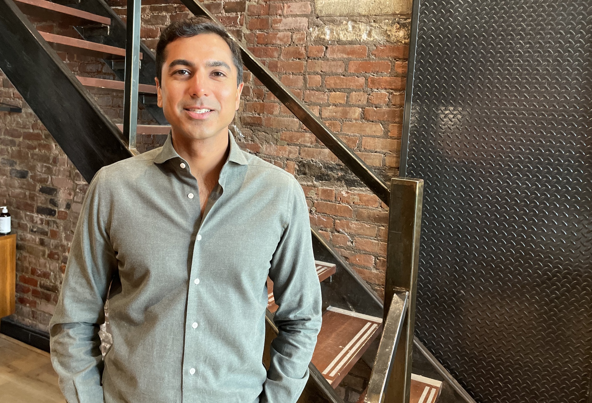 Amish Tolia standing beside an exposed brick wall and metal staircase in SoHo