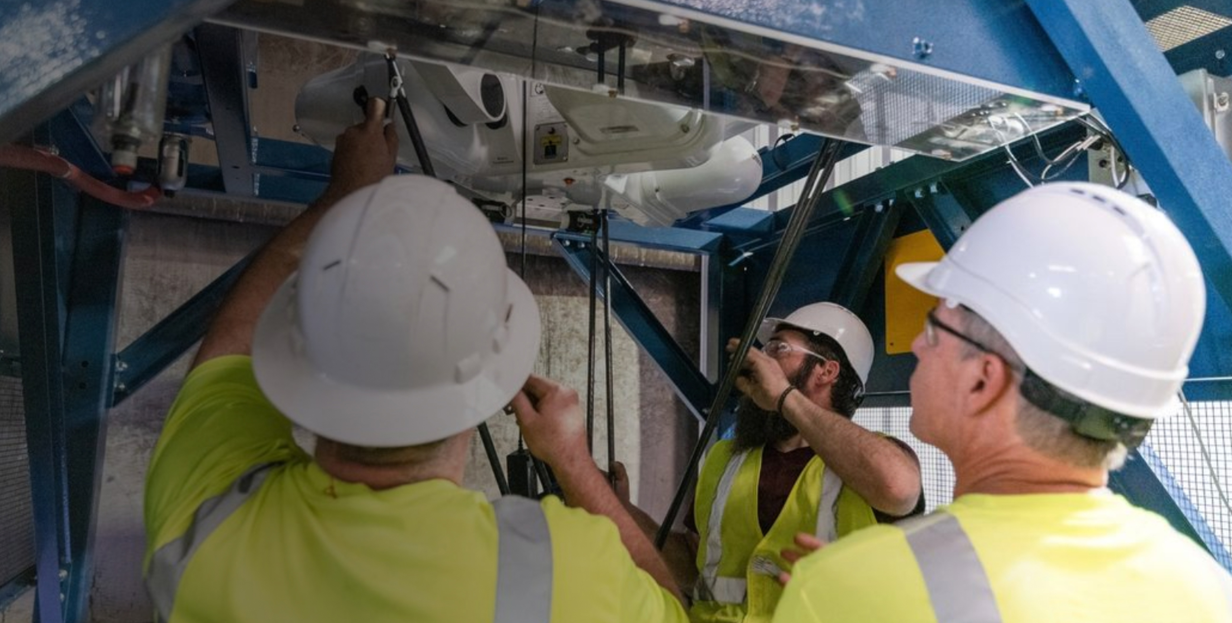 AMP personnel in hard hats inspecting industrial sorting equipment