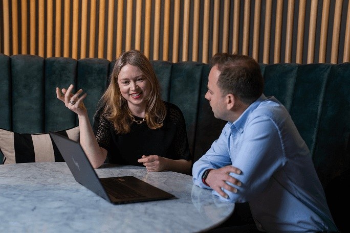 Two colleagues discussing work beside an open laptop