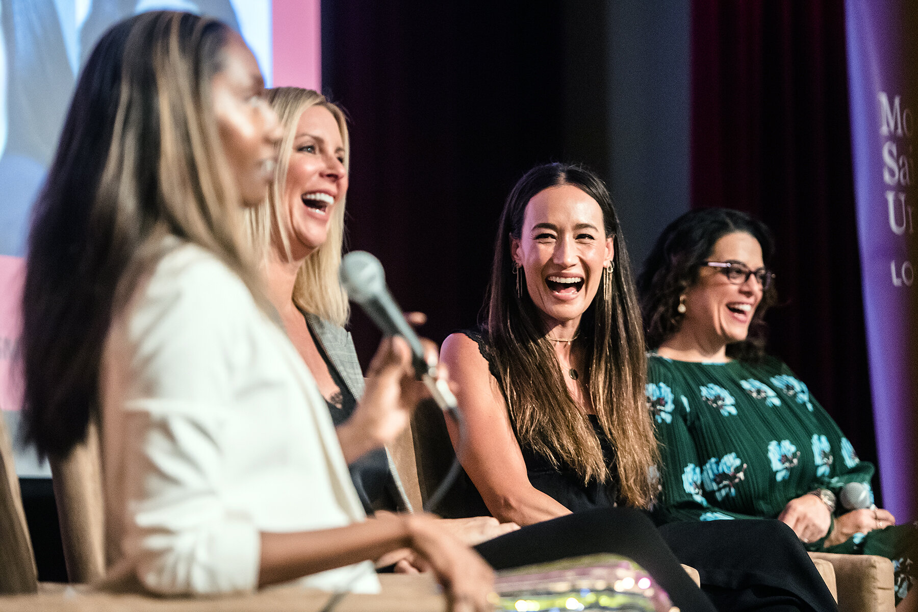 Joy Donnell, Amy Denoon, Maggie Q and Jess Weiner laughing together on a conference panel