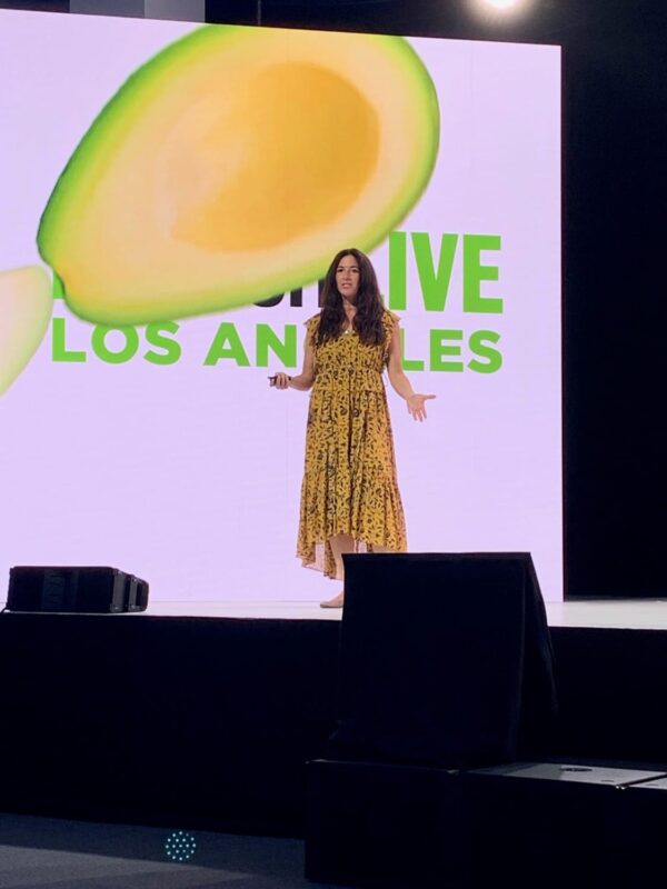 Amy Stanton speaking on a stage beneath a Los Angeles event graphic