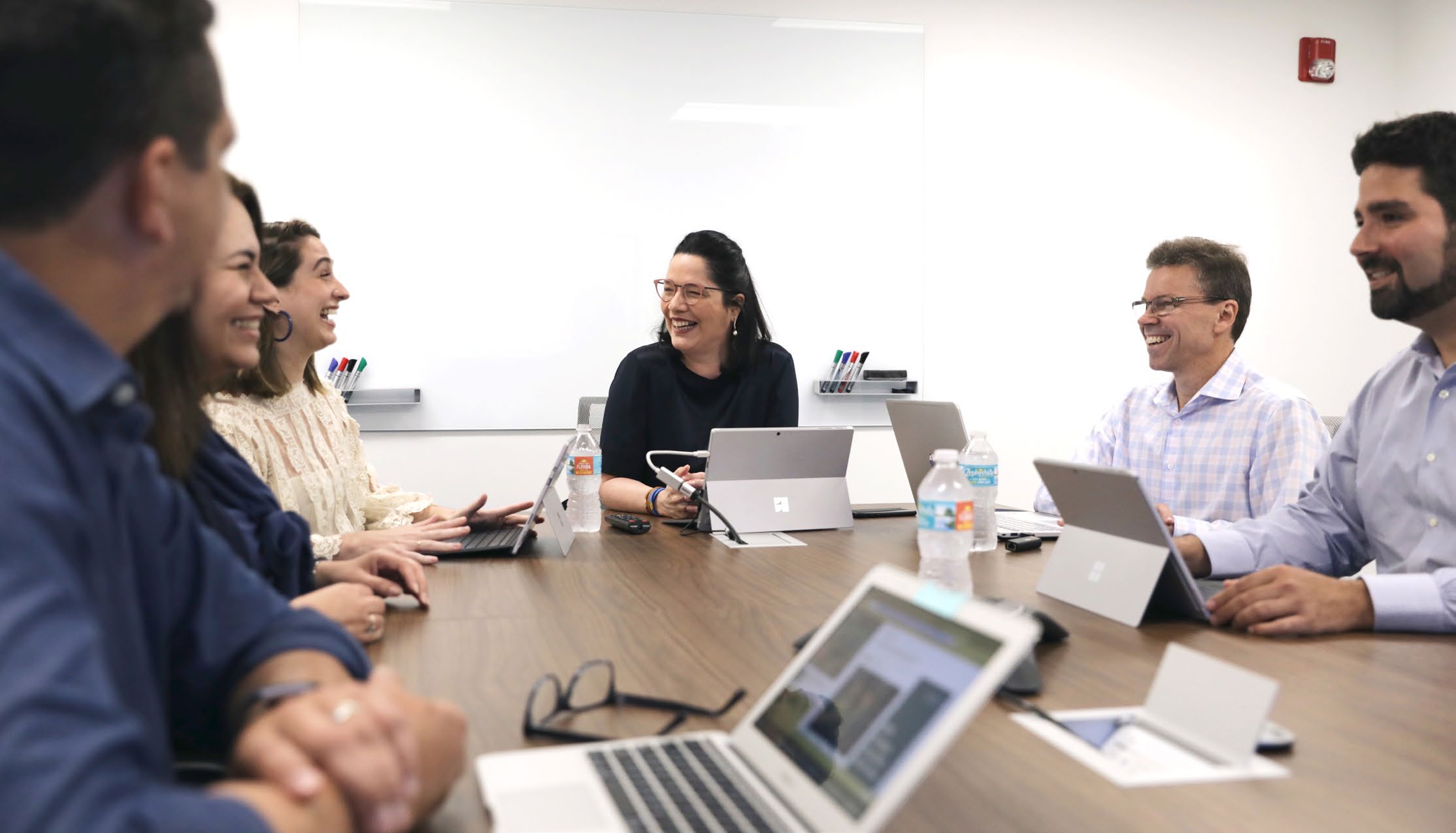 Anabel Perez, seated at the centre of a conference table, talking with colleagues