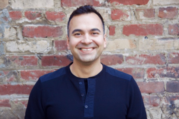 Anand Janefalkar smiling in front of a brick wall
