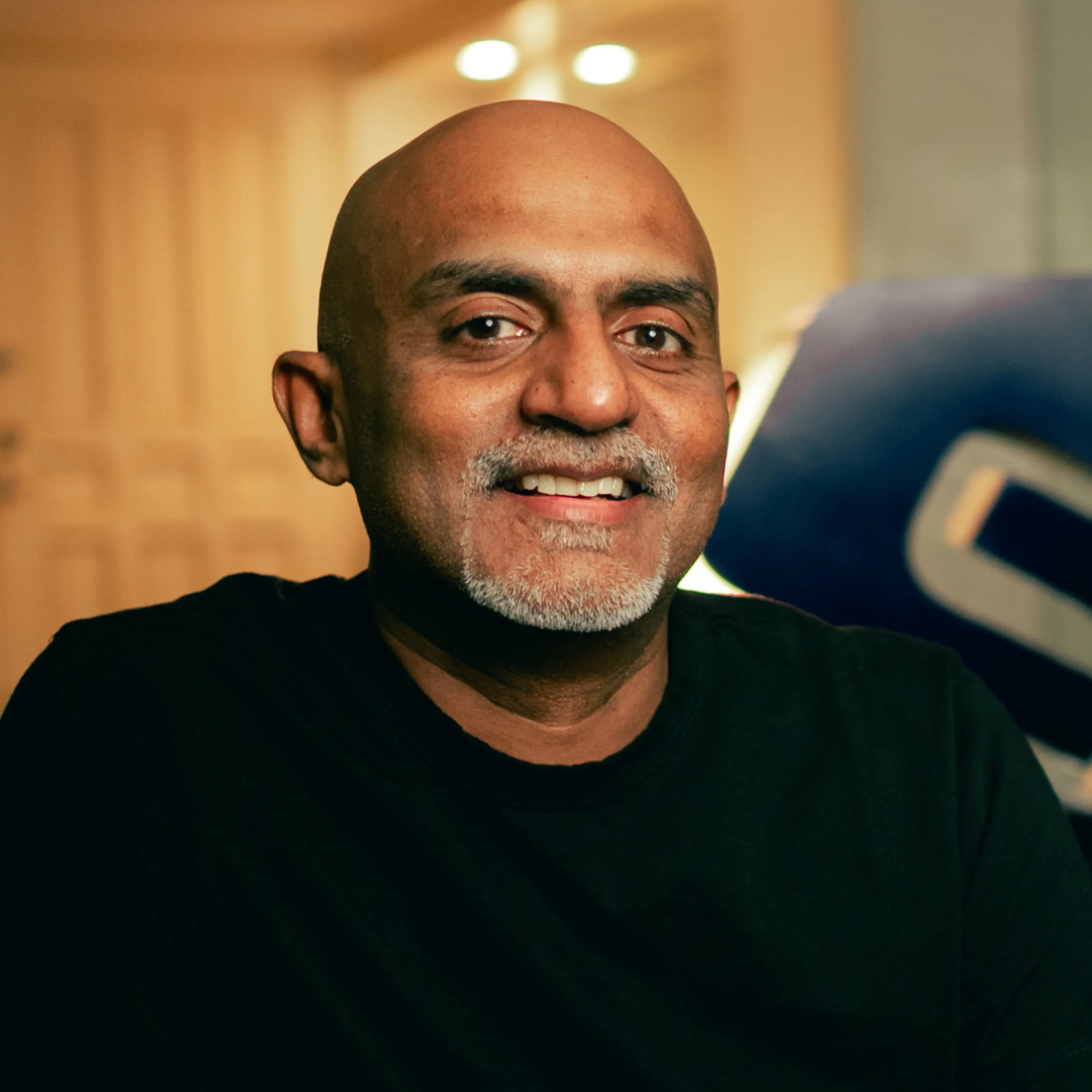 Anand Krishnan speaking into a microphone in the photograph accompanying his Fractional podcast interview
