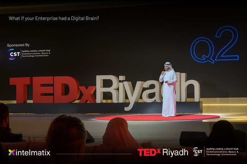 Anas Alfaris speaking on the TEDx Riyadh stage beneath a question about an enterprise having a digital brain