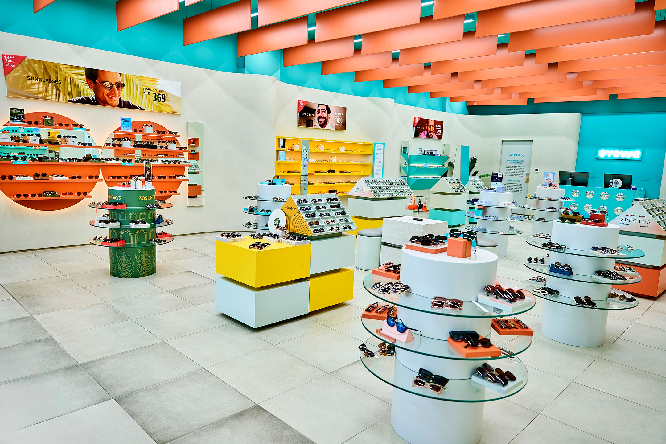 An eyewa shop interior with turquoise walls, orange ceiling panels and eyewear displays
