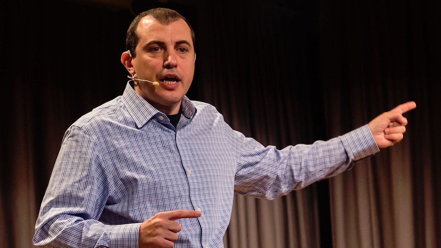 Andreas M. Antonopoulos speaking on stage with a headset microphone