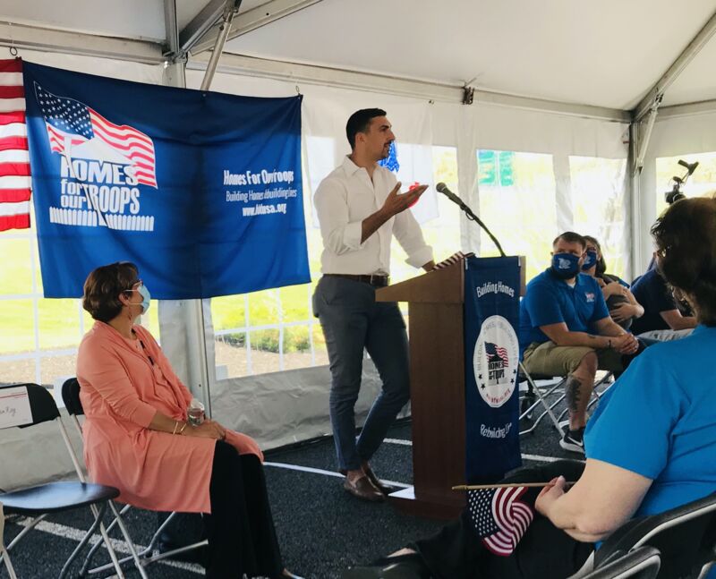 Andreas Kellas speaking at a podium during a Homes For Our Troops event