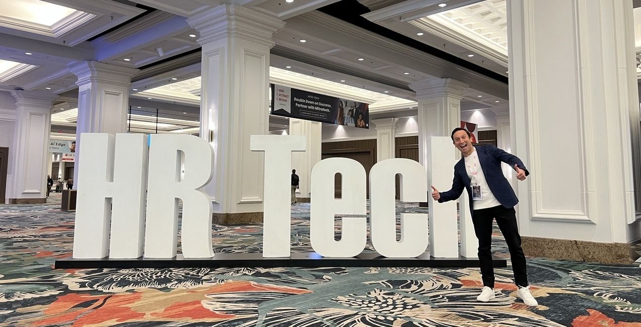 Andres Blank smiling beside large HR Tech letters at a recruiting industry conference