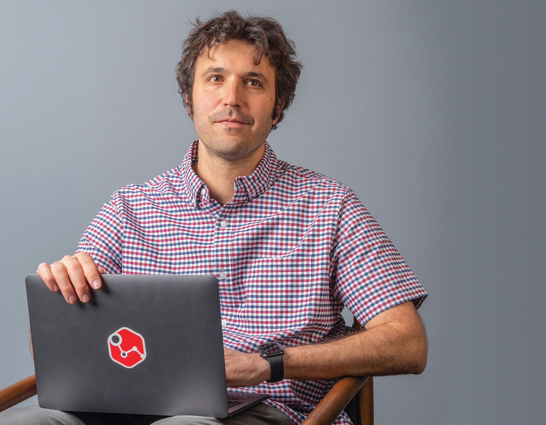 Andrew Beck seated with a laptop bearing a PathAI sticker, photographed by David DelPoio