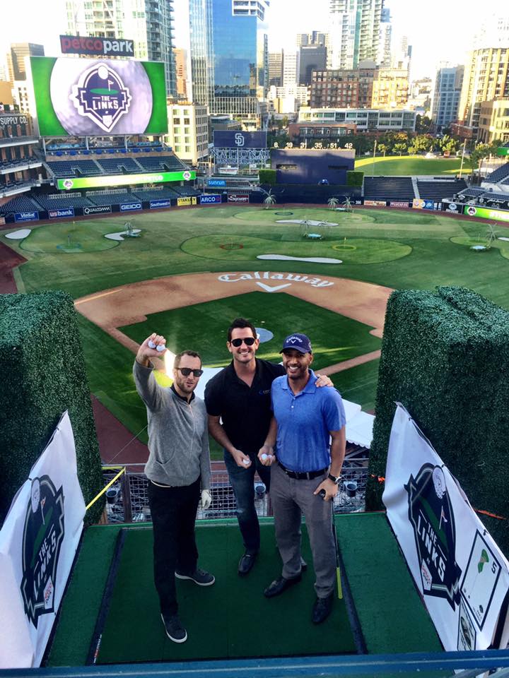 Three people at Petco Park with the baseball field arranged for a golf event