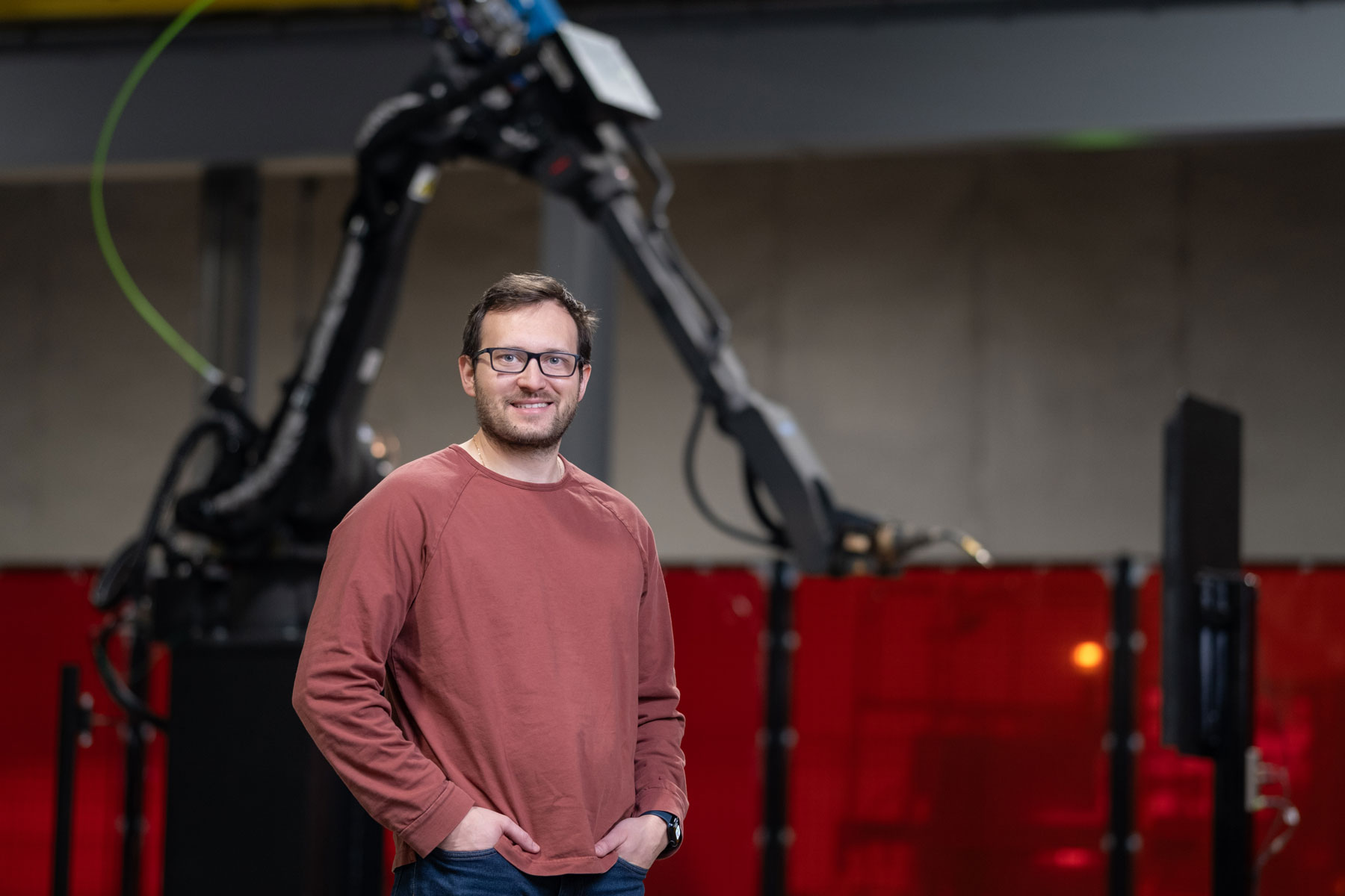Andrew Lonsberry standing on the Path Robotics factory floor in front of a robotic welding arm