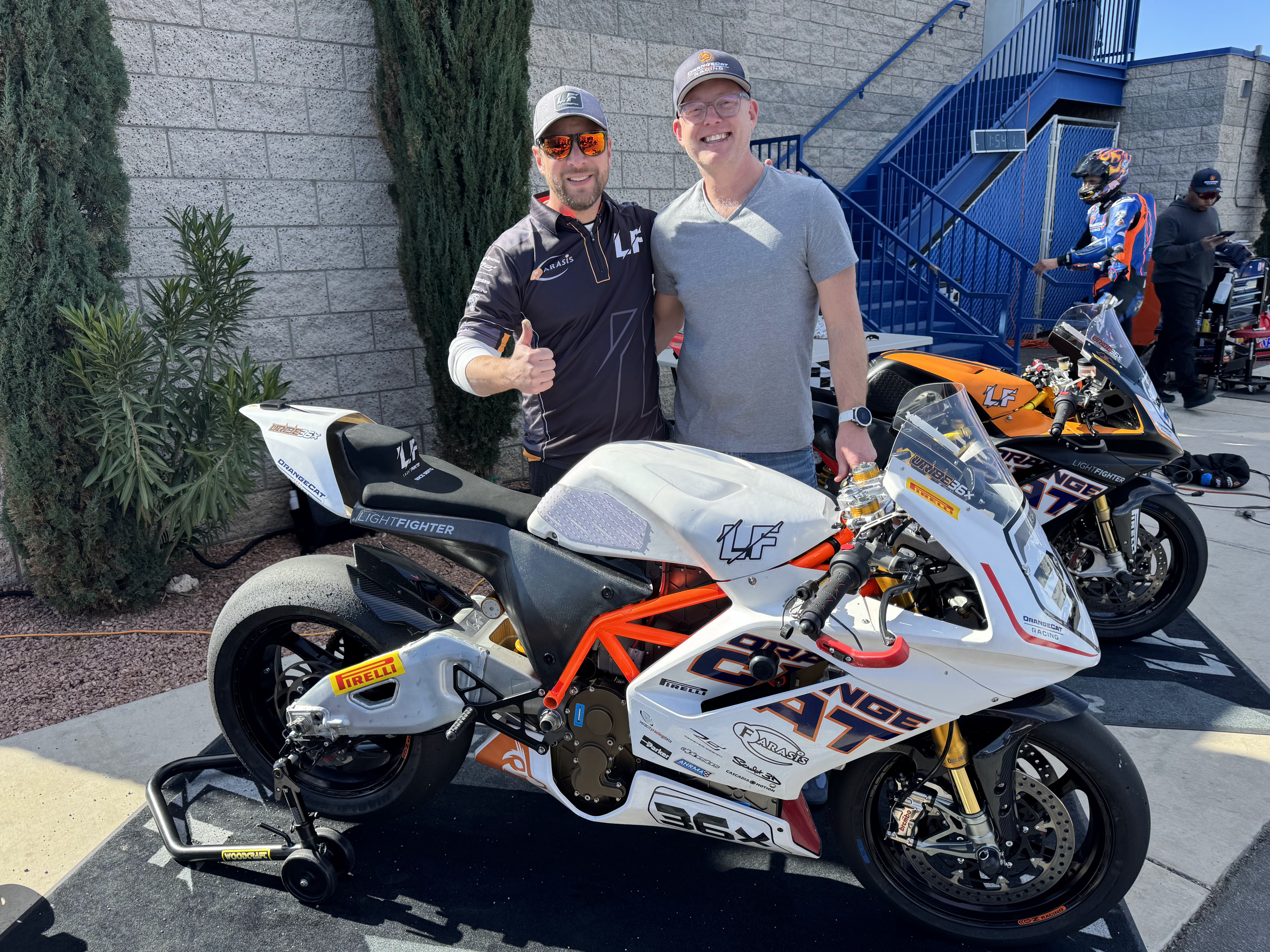 Andrew Sieja with a fellow racing enthusiast beside Lightfighter electric racing motorcycles